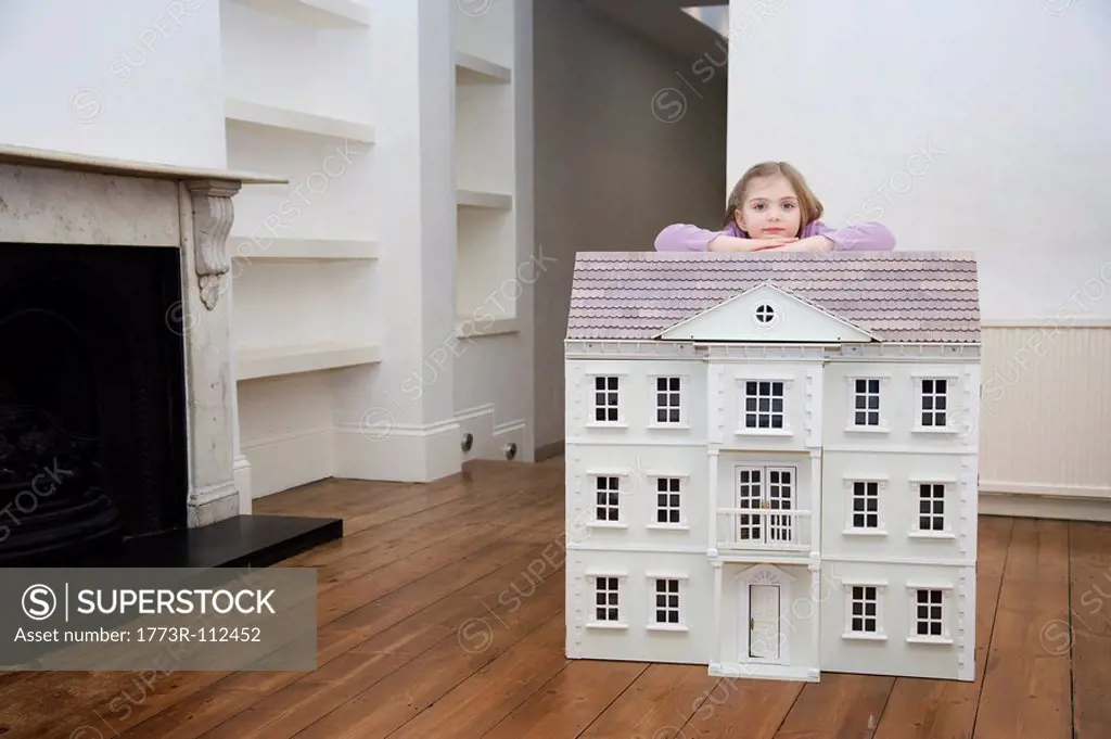 A girl resting on her dollhouse.