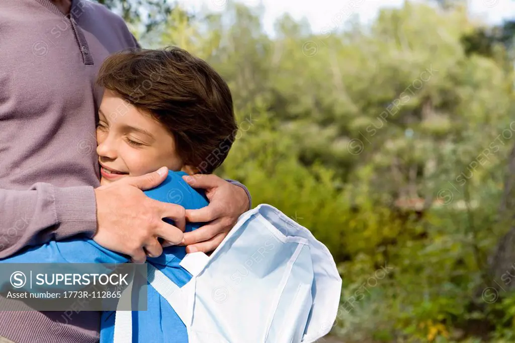 happy boy hugging dad back from school