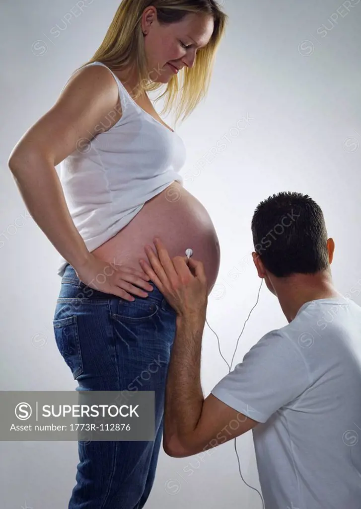 pregnant woman man listens on headphones