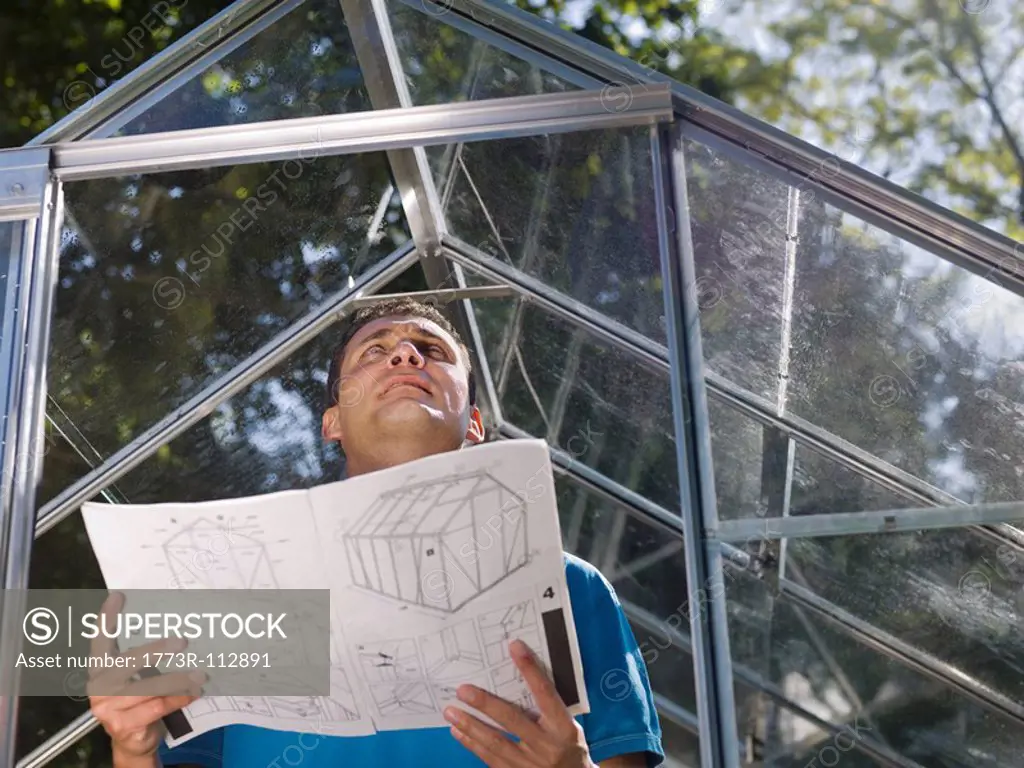 Man with greenhouse plans in garden