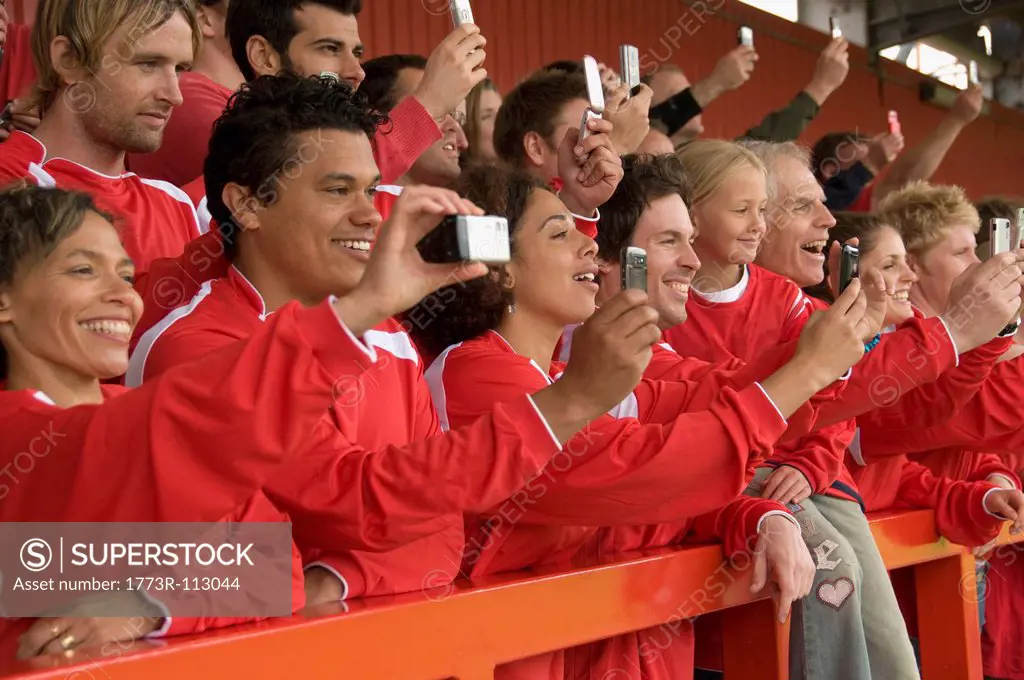Fans taking photographs at football match