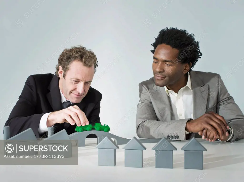 Two business men play with a train
