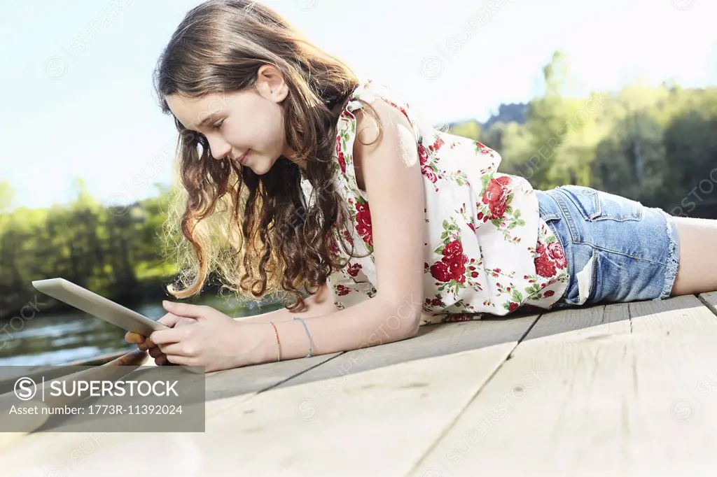 Girl using digital tablet on jetty