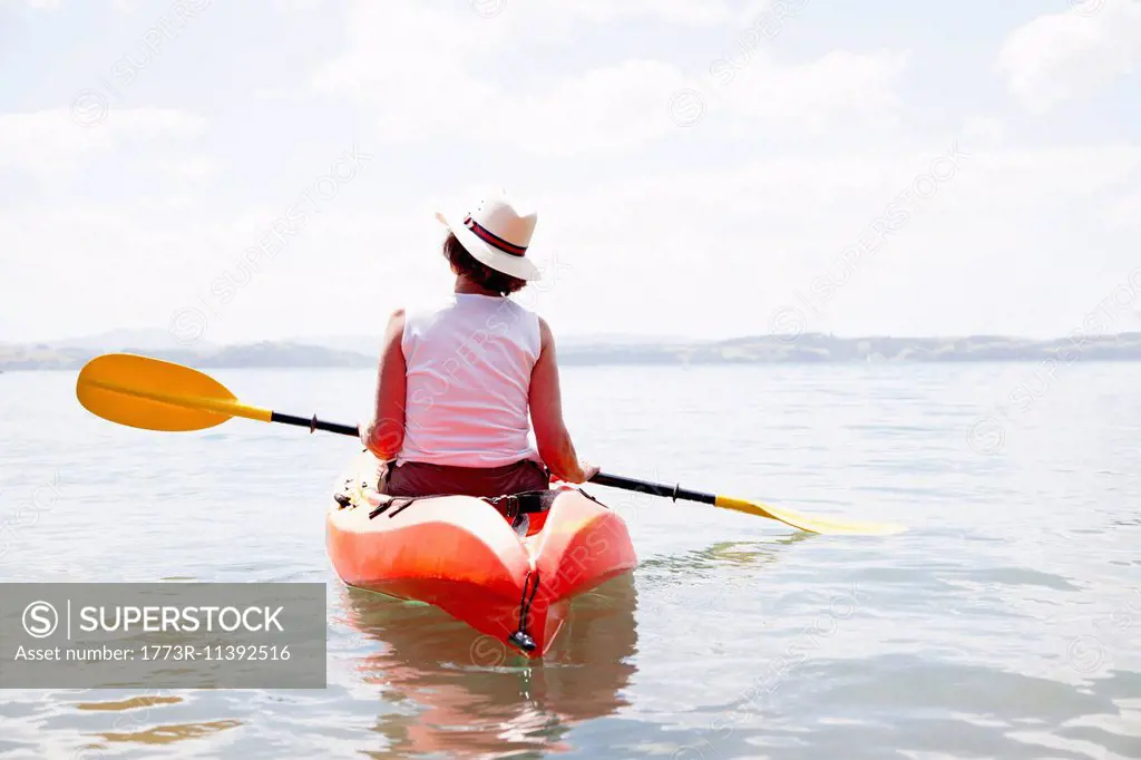 Rear view of senior woman sea kayaking