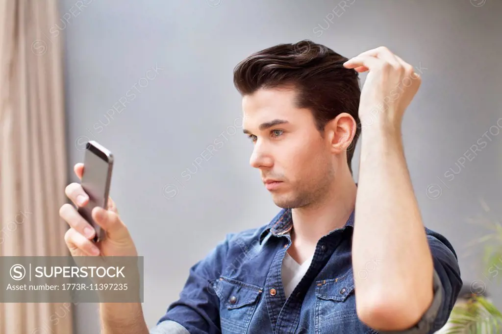 Young man taking selfie on smartphone in living room