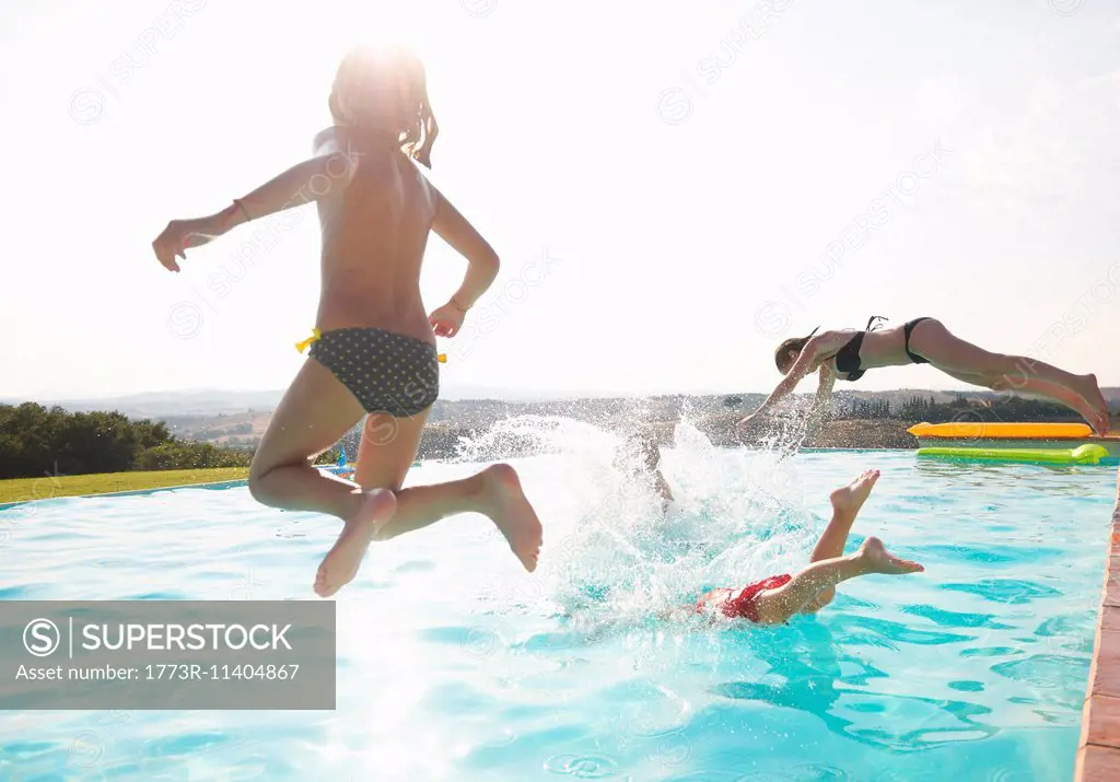 Three people jumping into swimming pool