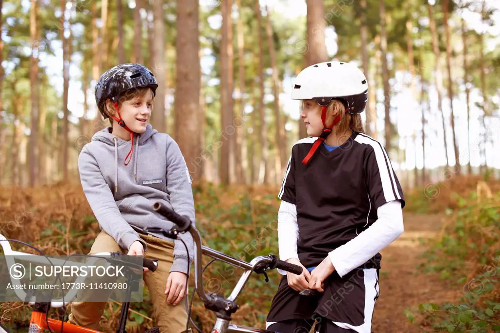 Twin brothers on BMX bikes chatting in forest