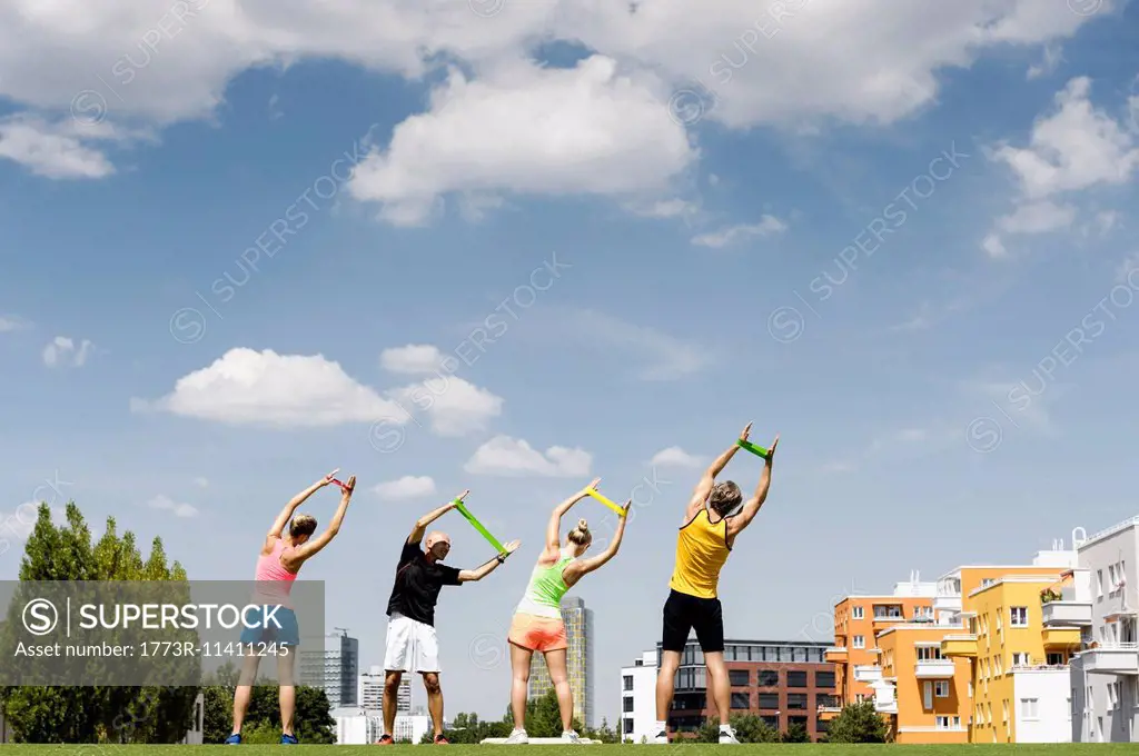 Four people exercising with rubber bands in park