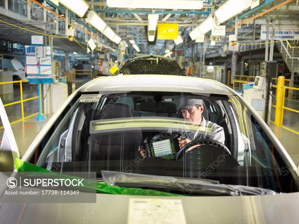 Car Worker In Car On Production Line