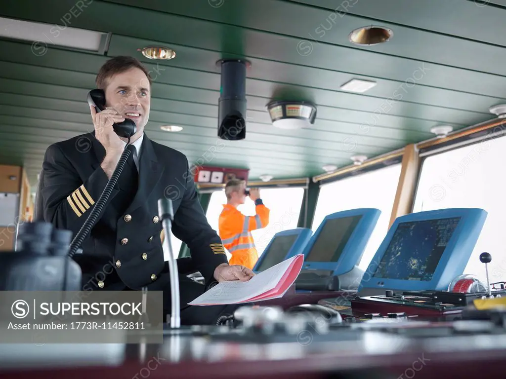 Captain using telephone on bridge of ship