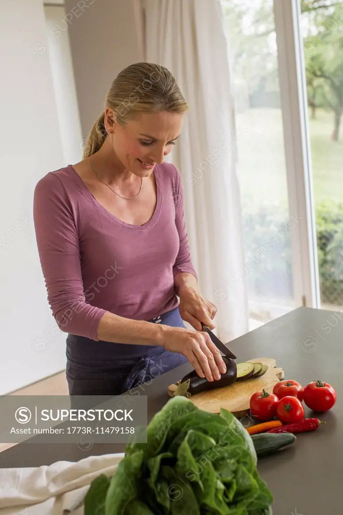 Mature woman slicing aubergine