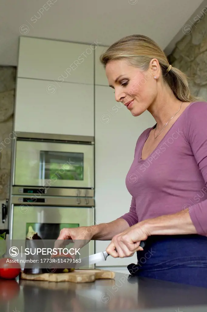 Mature woman slicing vegetables