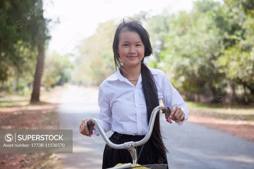 Cambodia girl with her bike on country road, Siem Reap, Cambodia