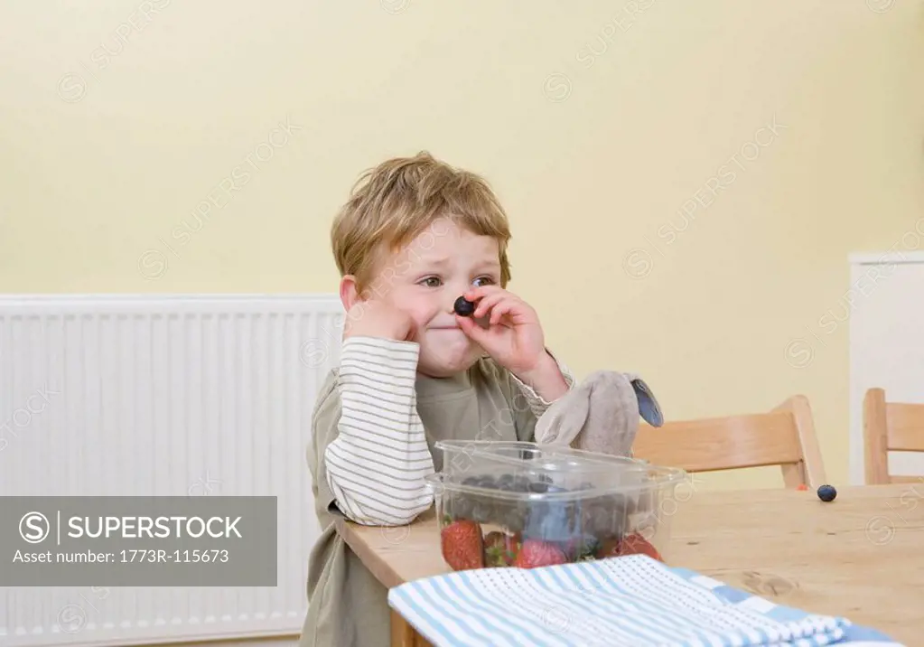 boy holding berry on nose