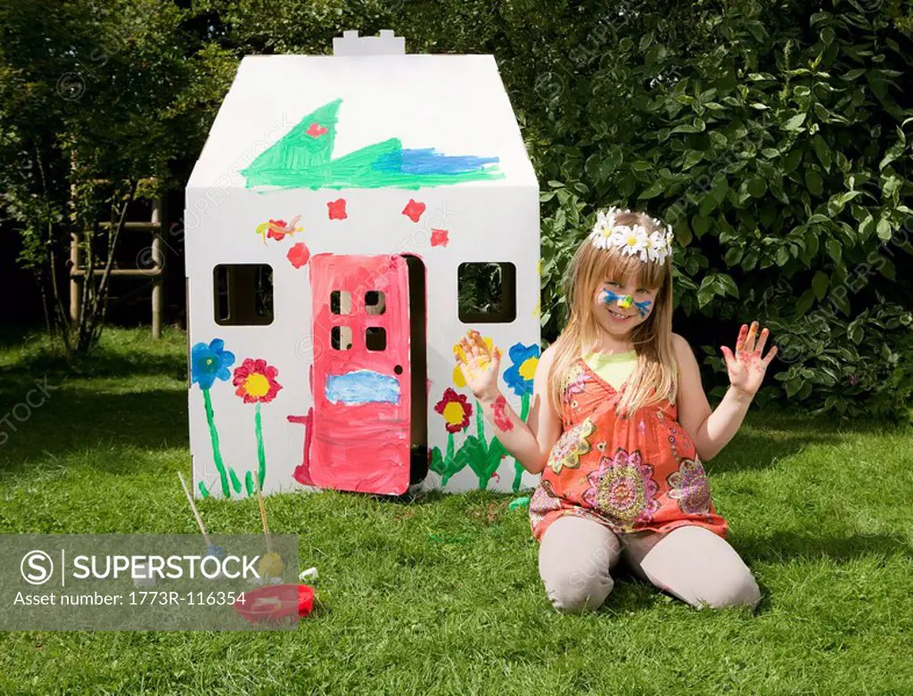 A girl outside her painted wendy house