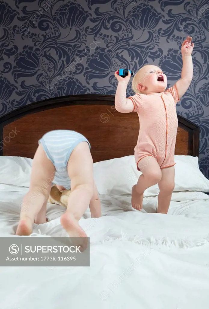 Two baby boys play on a bed