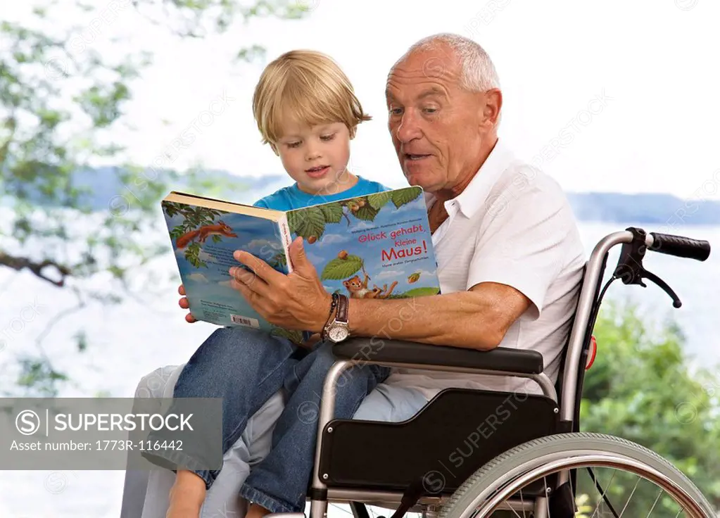senior man reading book to boy