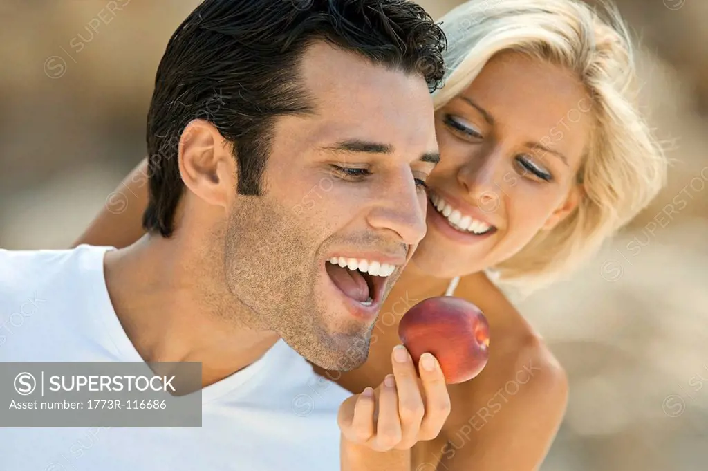 A female feeding a latin man an apple.