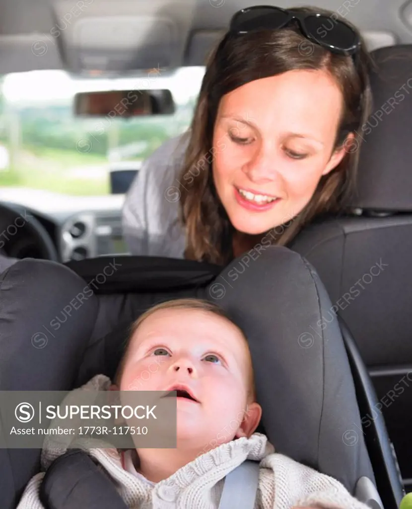 mother watching baby in car seat