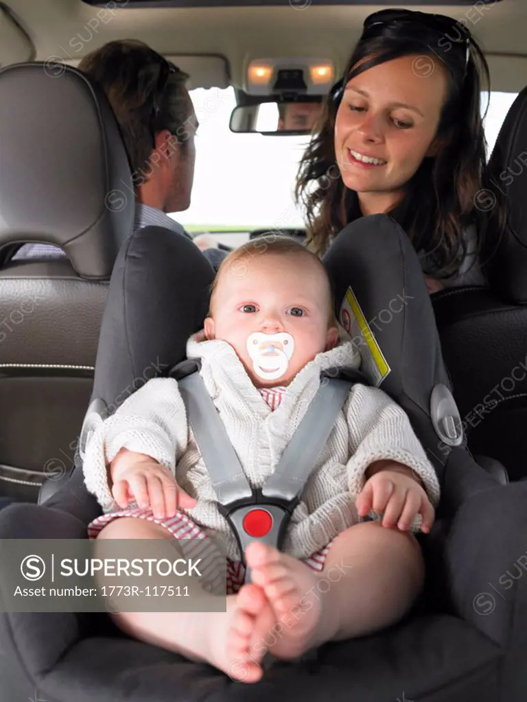 mother watching baby in car seat