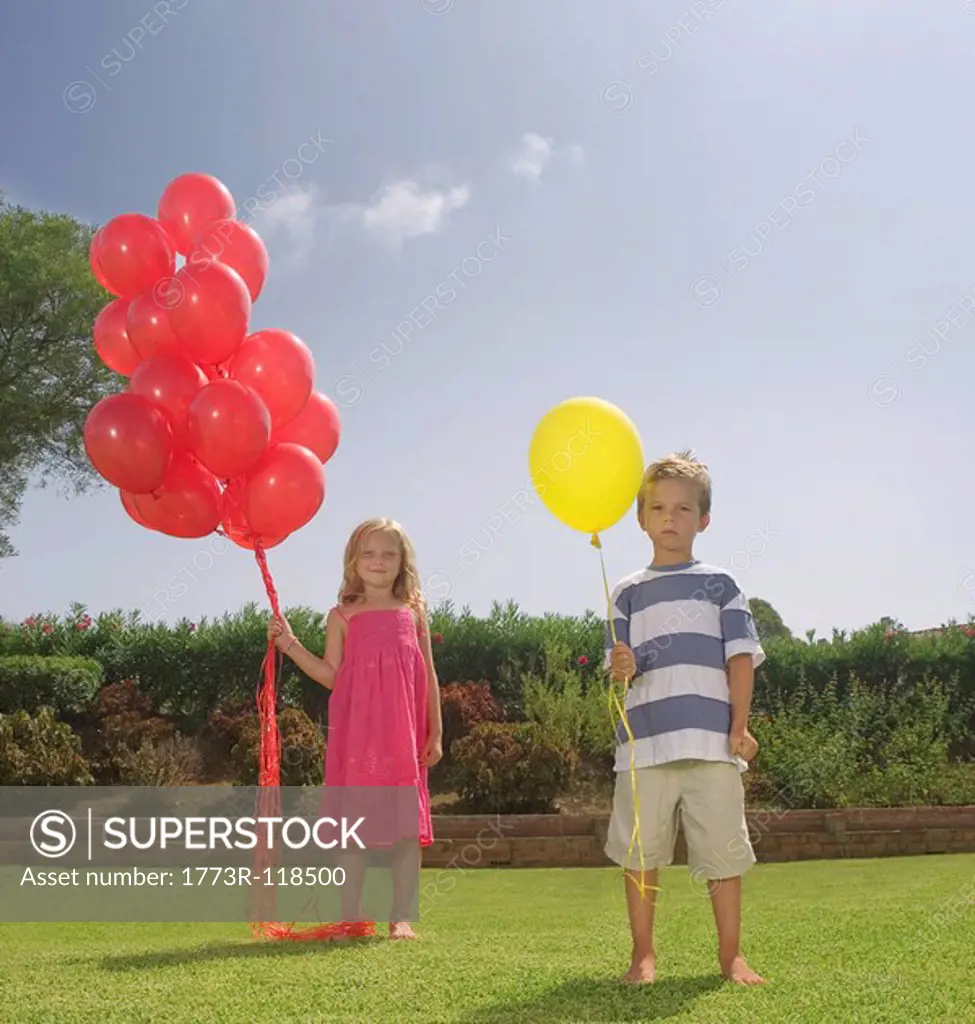 Young children holding red balloons