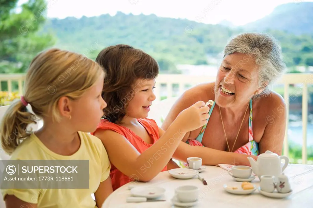 A senior female and children having tea