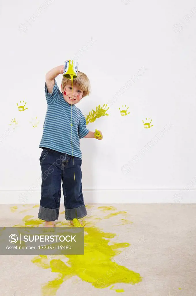 Toddler boy pouring paint onto carpet