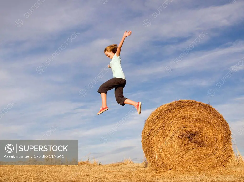 girl jumping from hay bale