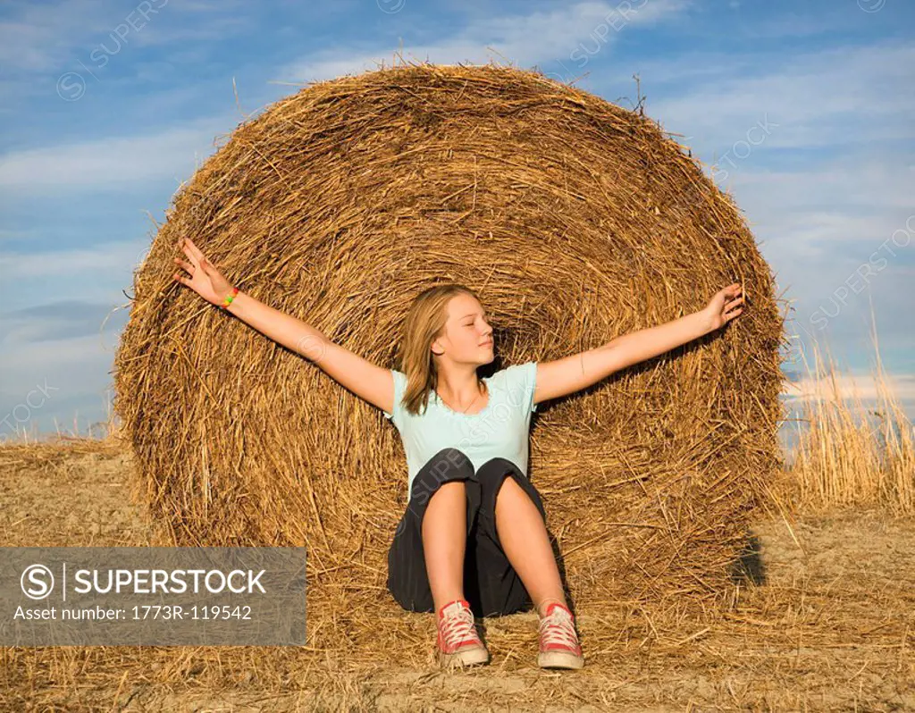 girl sitting in front of hay bale