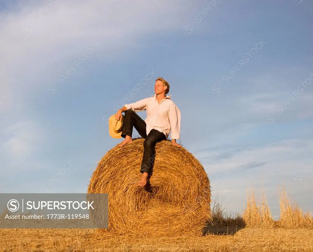 man sitting on hay bale