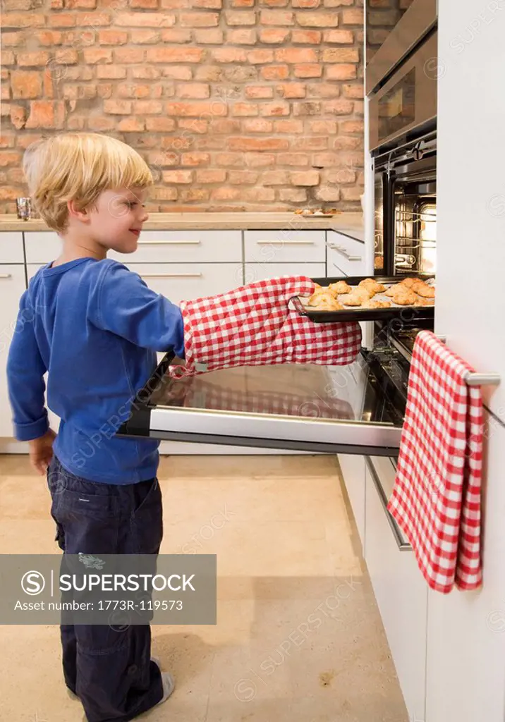 boy taking baked cookies from oven