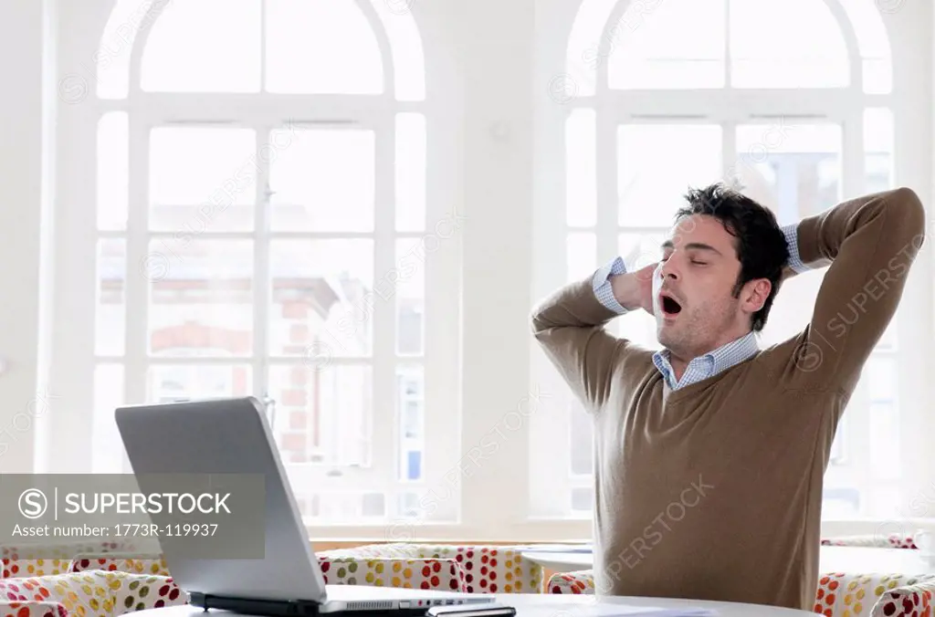 Young man yawning at office