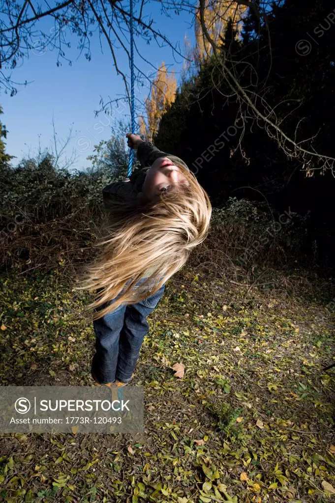 Girl standing on a tree swing