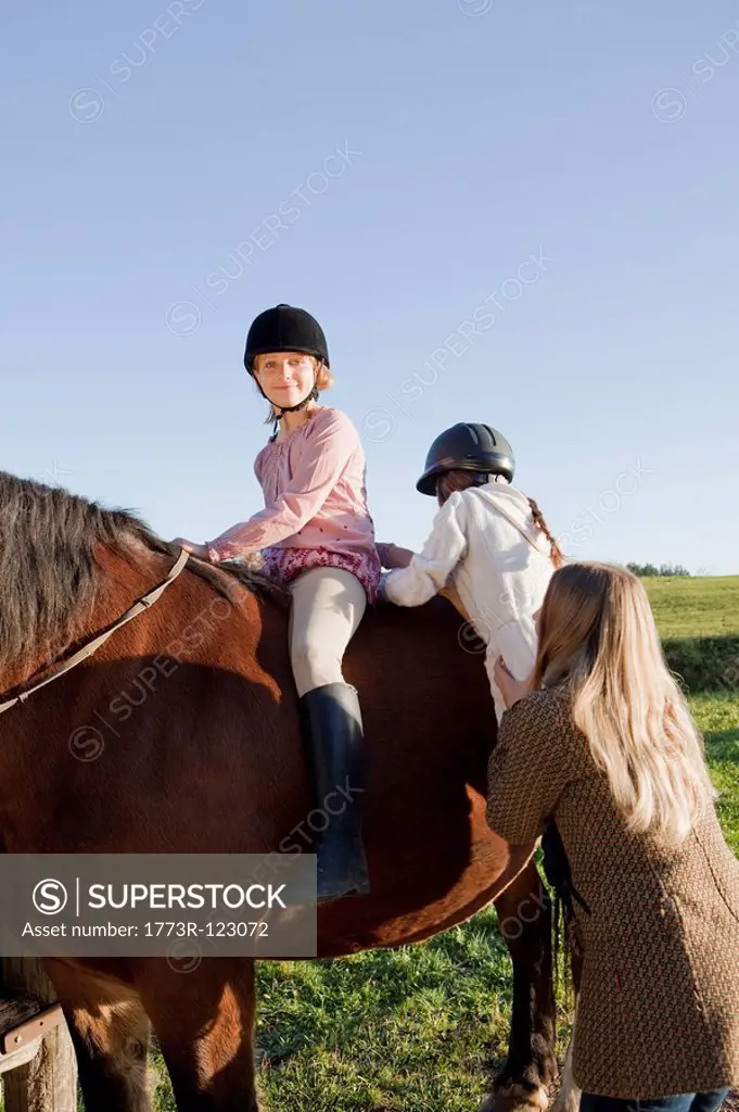 Woman helping girls on horseback