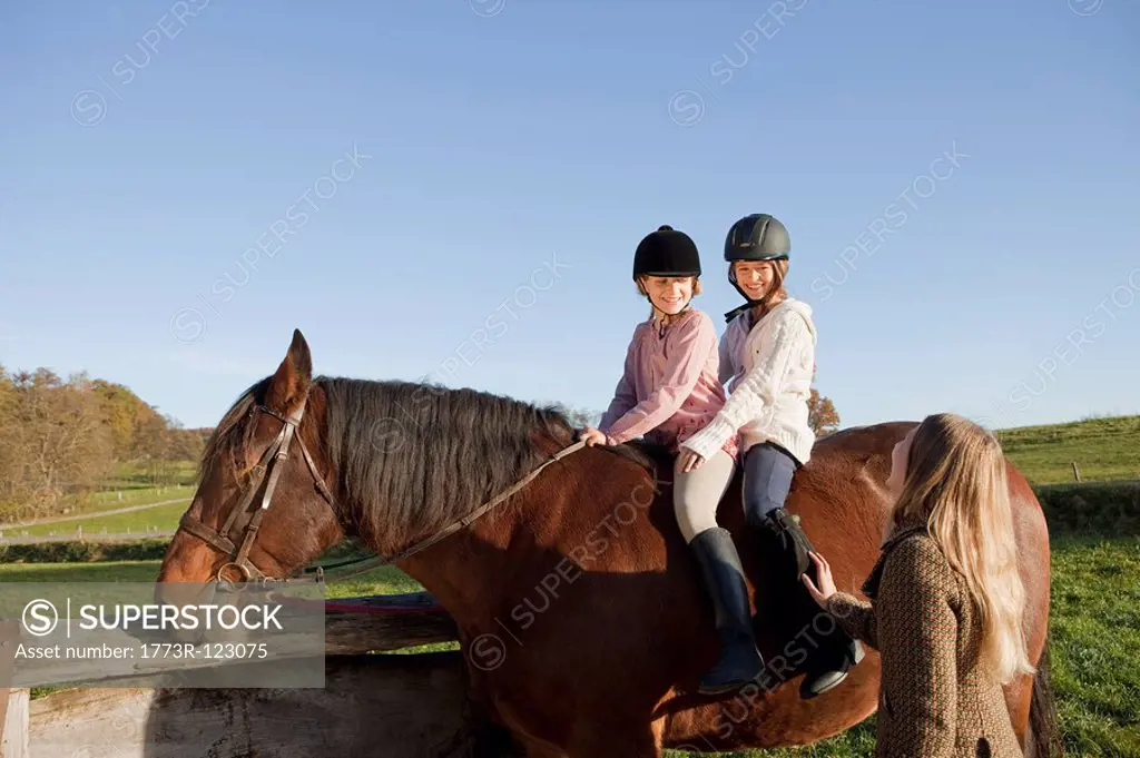 Woman talking with two girls on a horse