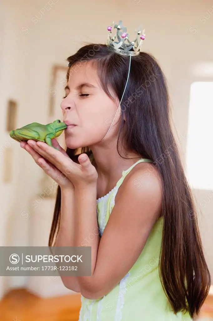 girl wearing crown kissing toy frog