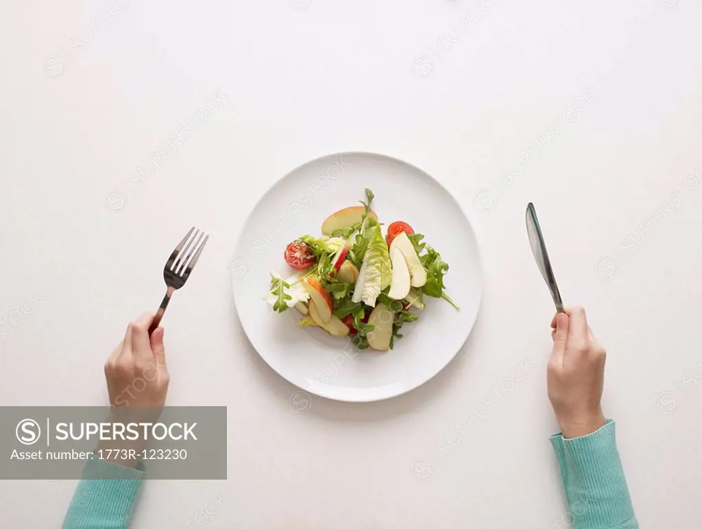 Hands by a plate of salad
