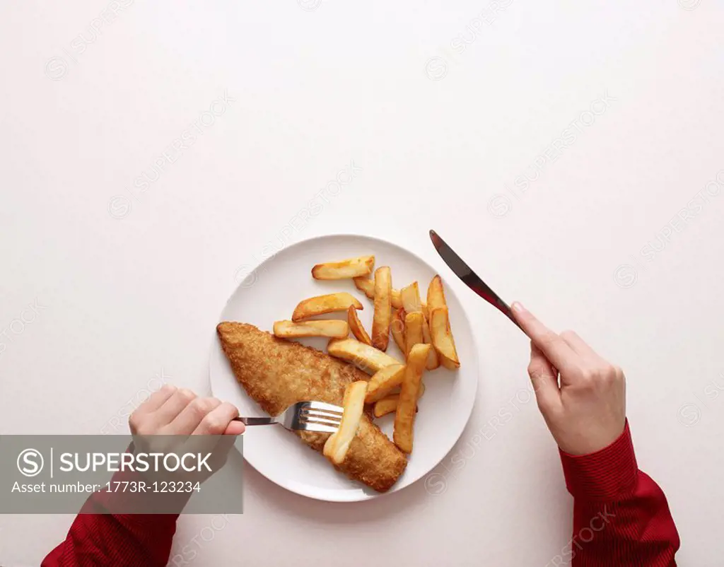 Hands by plate of fish and chips