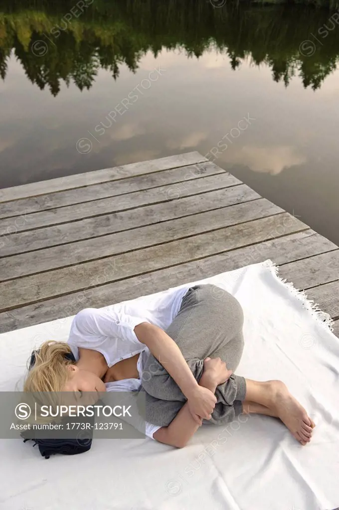 Young woman lying on blanket by lake