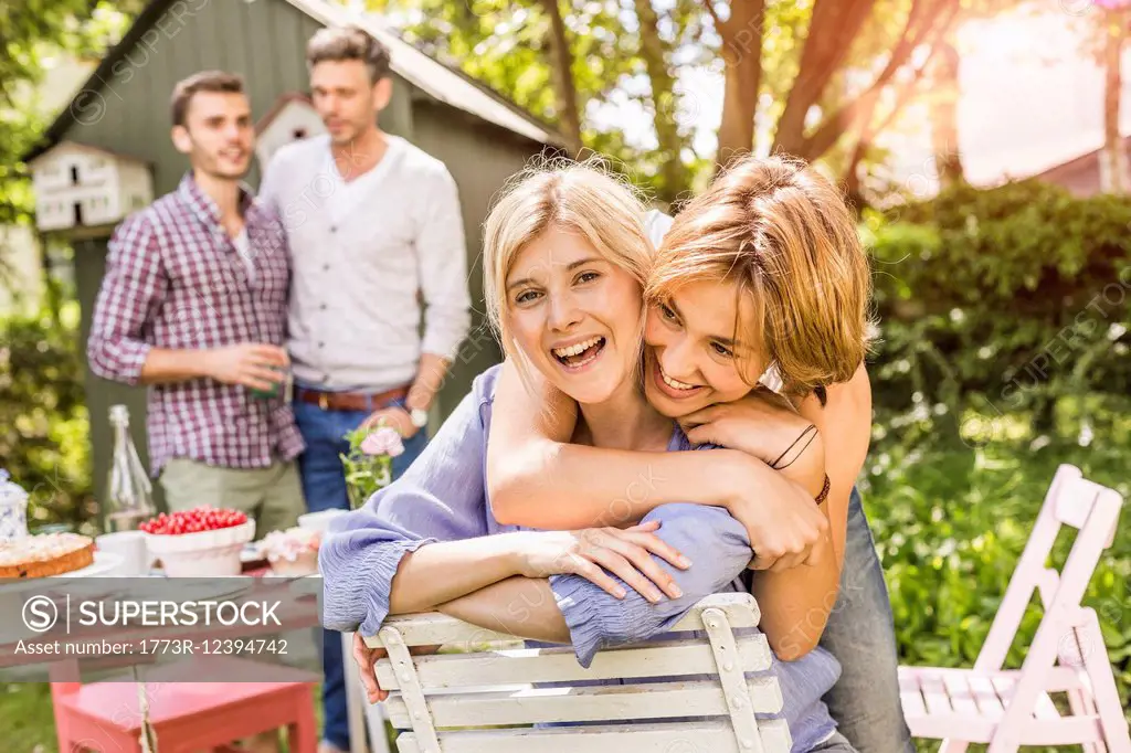 Group of friends at garden party,two female friends embracing