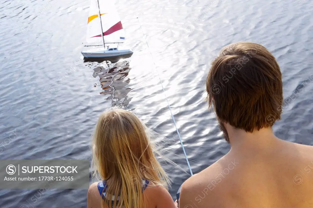 Father and daughter with rc boat on lake