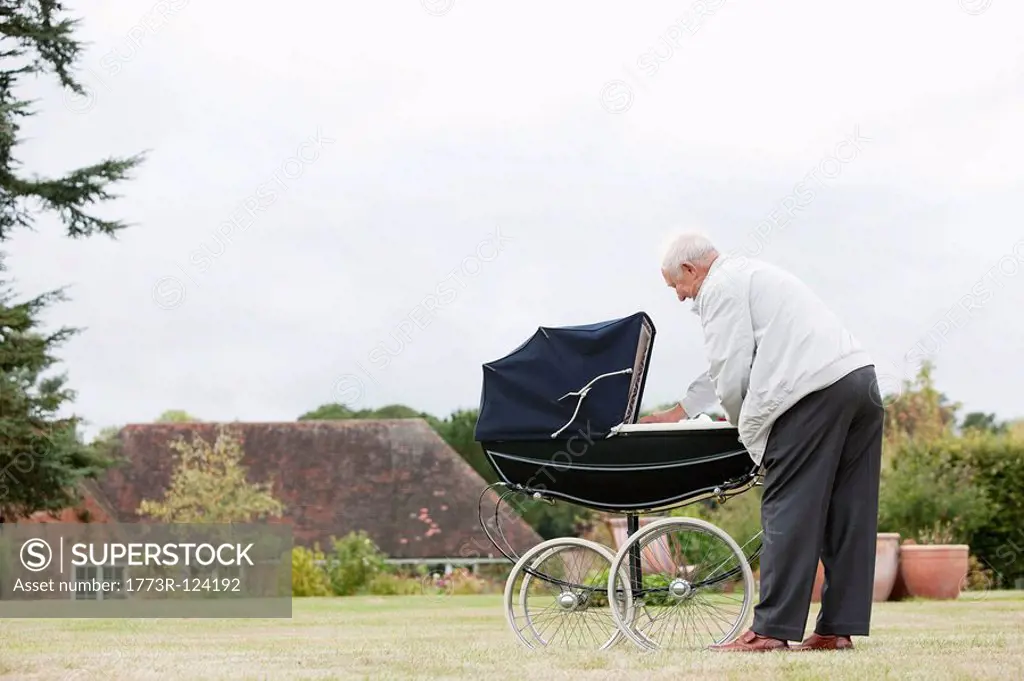 Grandfather looking at baby in pram