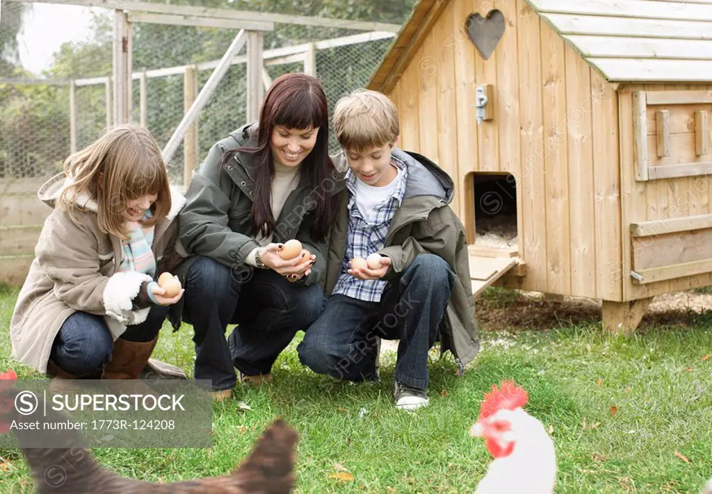 Mother and children feeding chickens