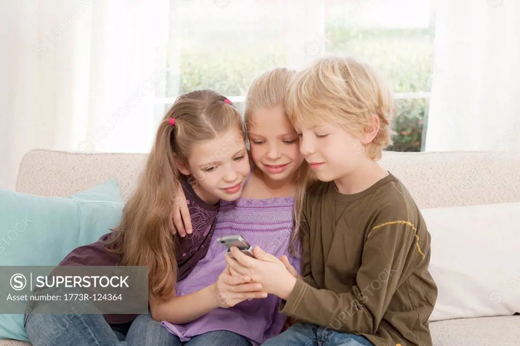 Three children looking at a mobile phone