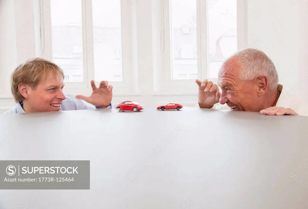 Businesspeople playing with toy cars