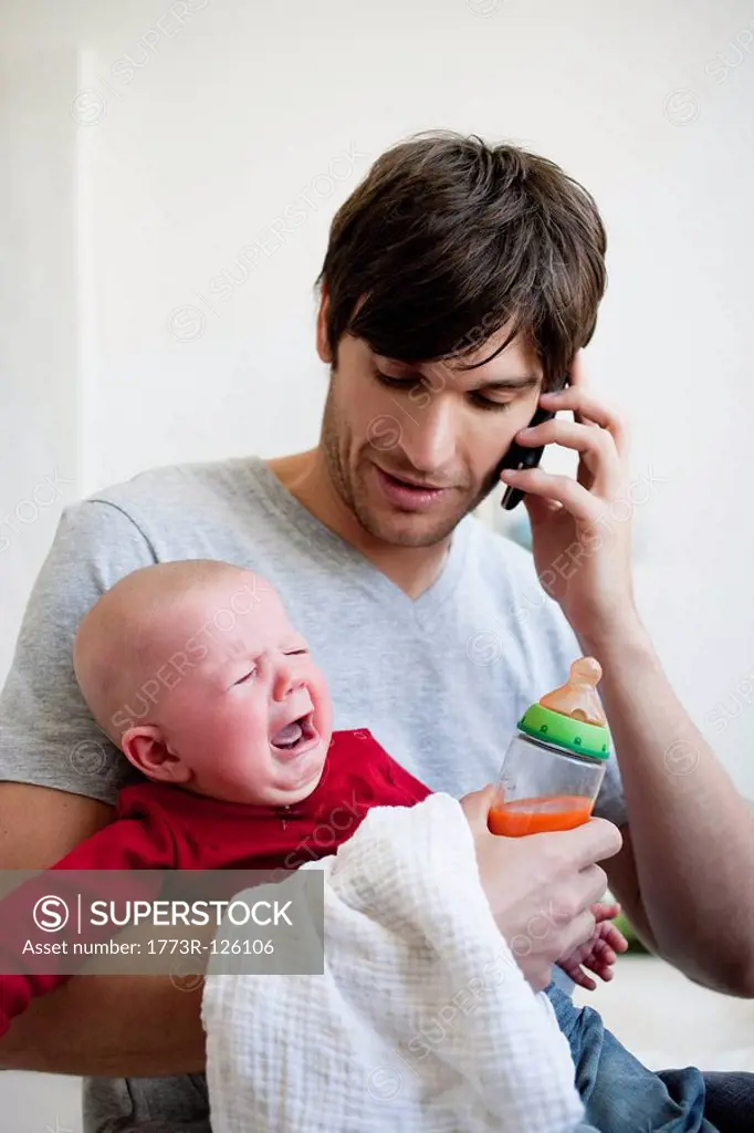 Man holding baby while phoning