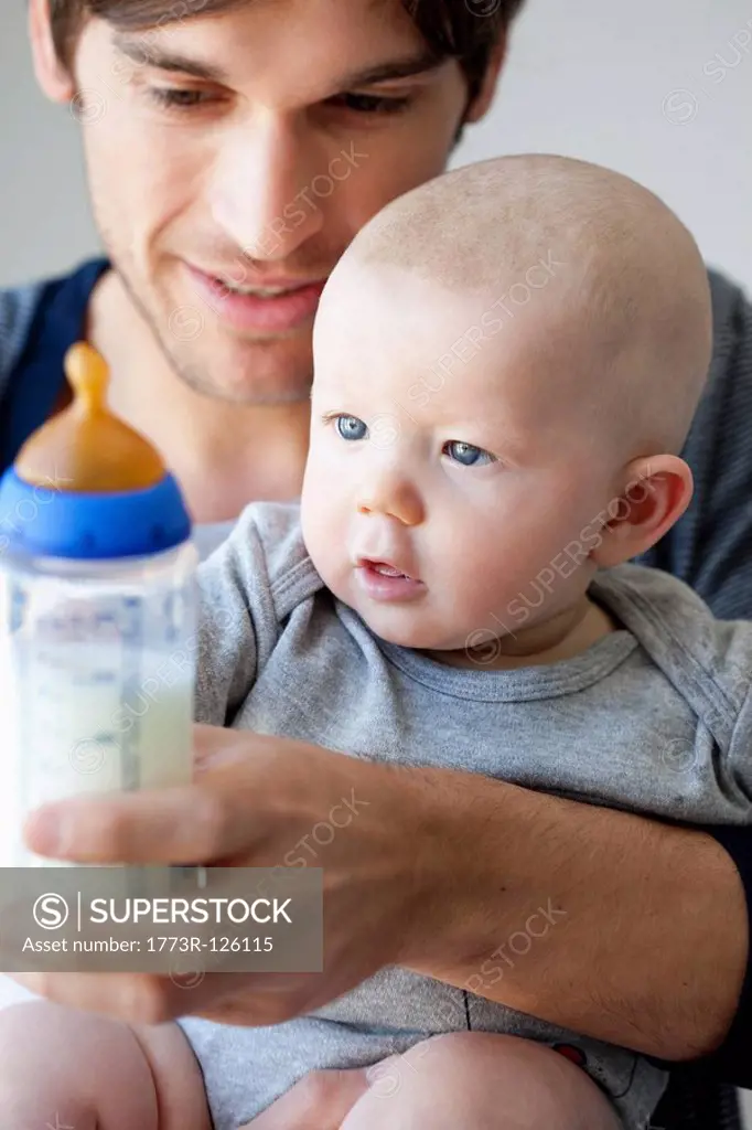 Father offering baby bottle