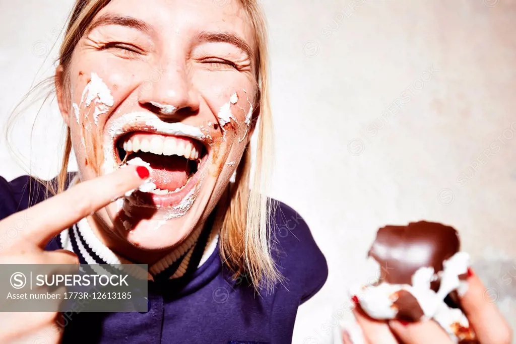 Close up studio shot of young woman with face covered in chocolate marshmallow