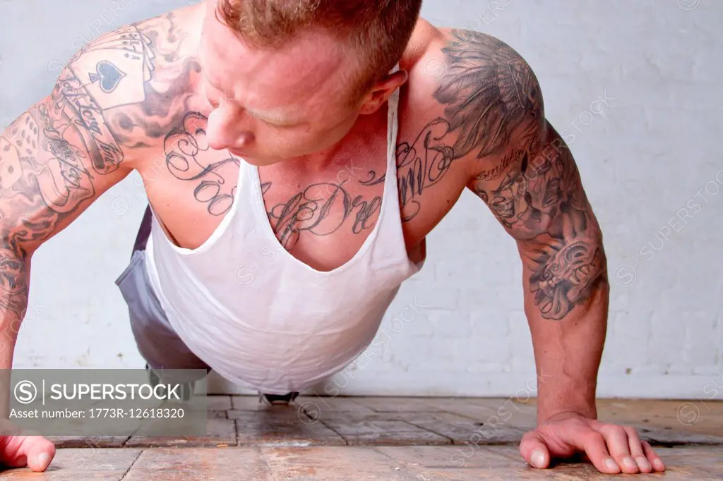 Young man with tattoos doing press ups