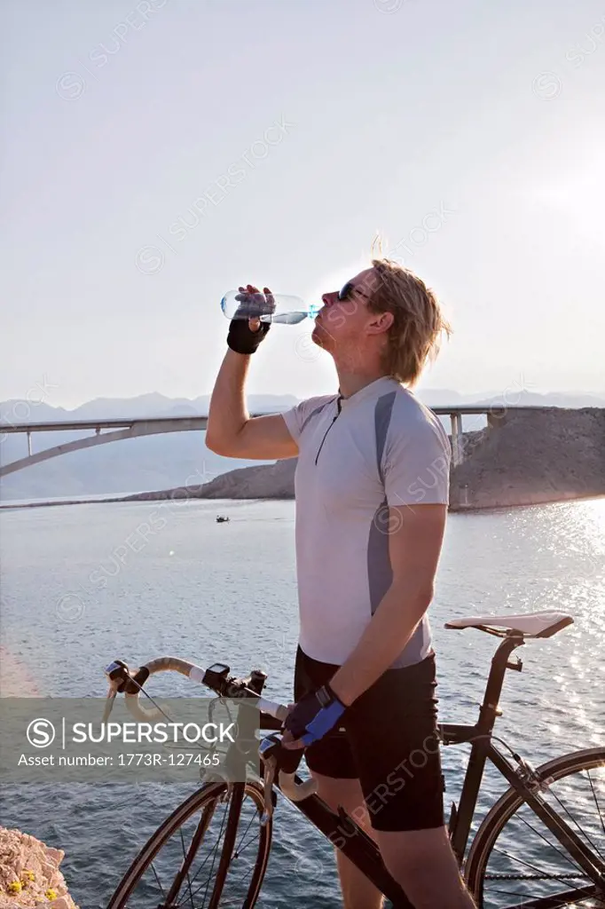 Cyclist drinking water by sea